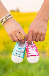 Cropped hand of couple holding baby shoes