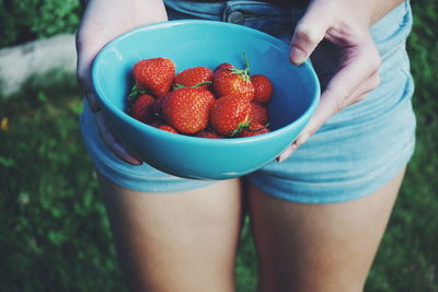 Mid section of woman holding strawberry