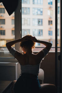Rear view of woman sitting against window