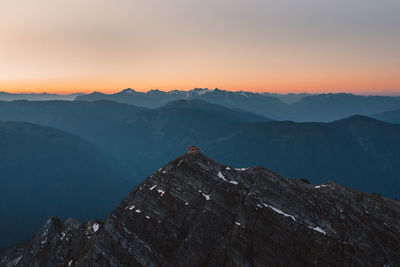 Scenic view of hut on summit of mountain against sky during sunset