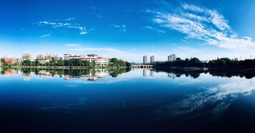 Scenic view of lake by buildings against blue sky