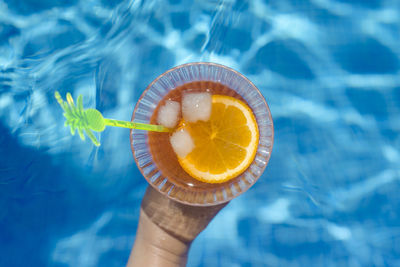 Close-up of hand holding drink at swimming pool