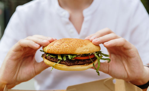 Midsection of woman holding burger