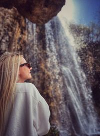 Rear view of woman standing against waterfall