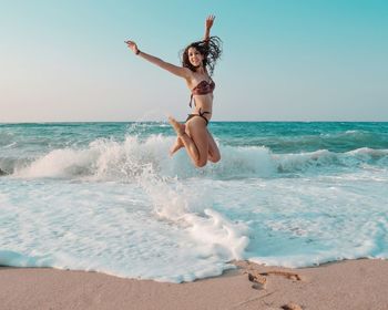 Full length of woman enjoying at beach against sky