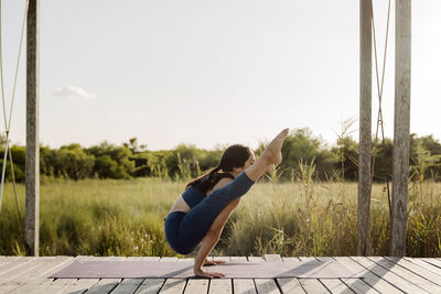 Strong woman doing tittibhasana yoga pose at gazebo