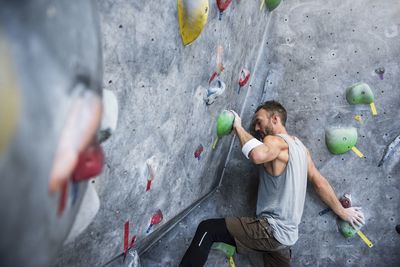 Determined athlete climbing on rock wall at gym