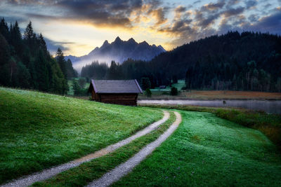 Scenic view of landscape against cloudy sky during sunset