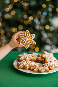 Ginger christmas cookies in children's hands on the background of the christmas tree.