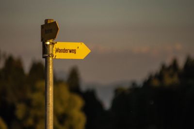 Close-up of road sign against sky