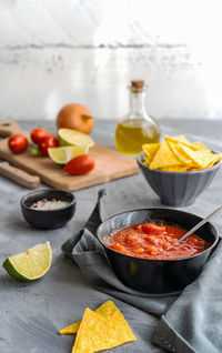 Tomato dip with nachos tortilla in bowl and main ingredients aside