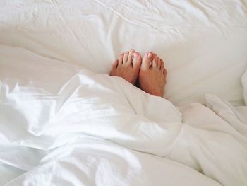 Low section of person resting on bed