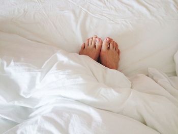 Low section of woman relaxing on bed