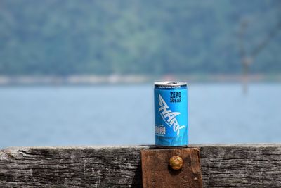 Close-up of text on wooden post by lake against sky