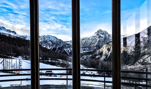 Snow covered mountains against sky seen through window