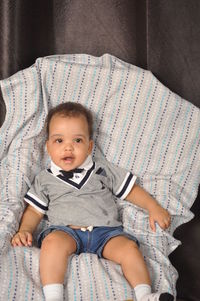 Portrait of cute baby boy sitting on sofa at home