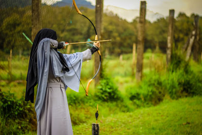 Archery aiming bow against trees