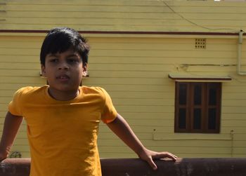 Portrait of boy standing against built structure