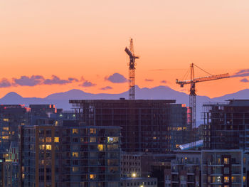 Construction site by buildings against sky during sunset