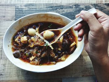 Cropped image of hand holding bowl of food