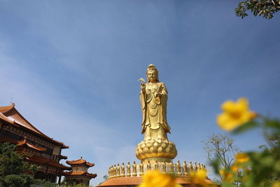 Low angle view of statue amidst buildings against sky