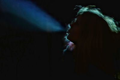 Teenage girl smoking cigarette in dark