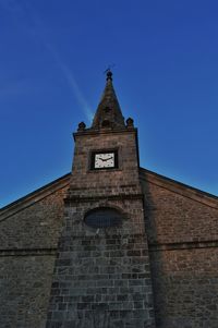 Low angle view of bell tower against blue sky