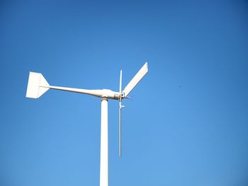 Low angle view of windmill against clear blue sky