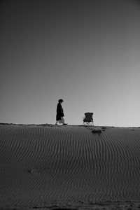 Silhouette men sitting on land against clear sky