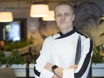 Portrait of confident chef with arms crossed standing at restaurant