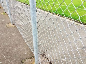 Chainlink fence by empty footpath