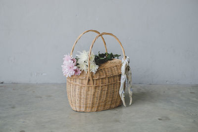 Flowers on basket over floor against wall