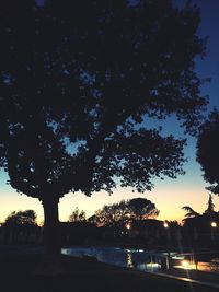 Silhouette trees by lake against sky during sunset