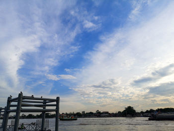 View of boats in river against cloudy sky