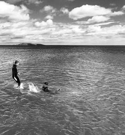 People in sea against sky