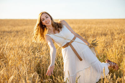 Young woman smiling while standing on field against sky