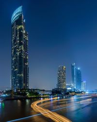 Illuminated modern buildings in city against sky at night