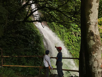 Rear view of man and woman on footbridge in forest