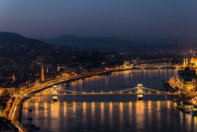 Illuminated bridge over river at night