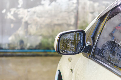 Close-up of wet side-view mirror on car