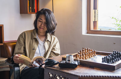 Woman reading book next to chess table at tea lodge in sri lanka