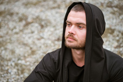 Portrait of young man outdoors with an unshaven face in a dark sweater