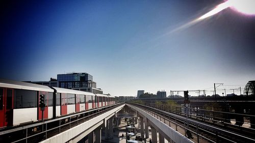 Railroad tracks in city against clear blue sky