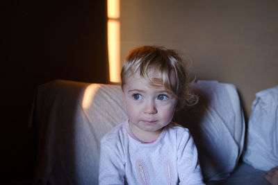 Portrait of cute boy sitting on sofa at home