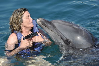 Close up photo of lady kissing a dolphin 