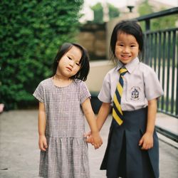 Portrait of girl wearing school uniform standing with sister