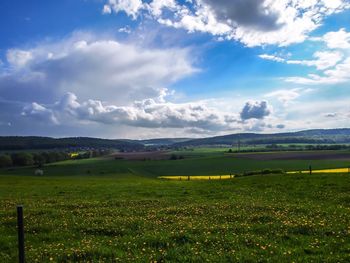 Scenic view of grassy field against cloudy sky