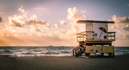 Lifeguard hut on beach against sky during sunset