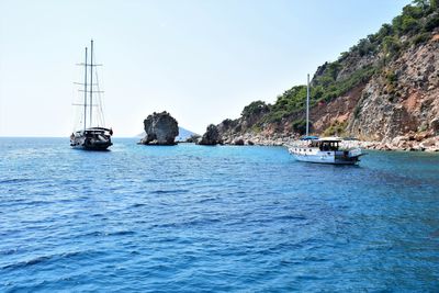 Sailboats sailing on sea against clear sky