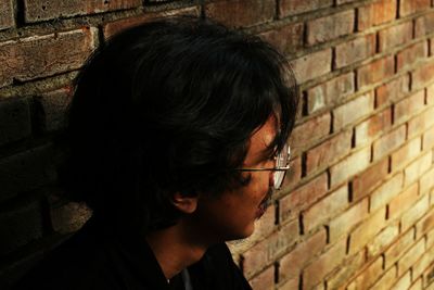 Close-up of woman standing against brick wall